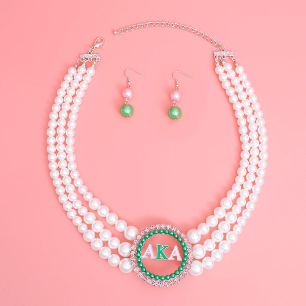 Alpha Kappa Alpha Inspired Pearl Necklace Set - Graduated white acrylic pearl necklace with green pearl studs and pink rhinestone-edged pendant. Includes matching double pearl drop earrings EJIJI Boutique