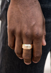 Image of a men's gold Paparazzi ring with a beveled band, delicately hammered for texture. The ring is displayed against a neutral background, showcasing its stylish design and flexible fit. Perfect accessory for any occasion. Available at Ejiji Boutique.